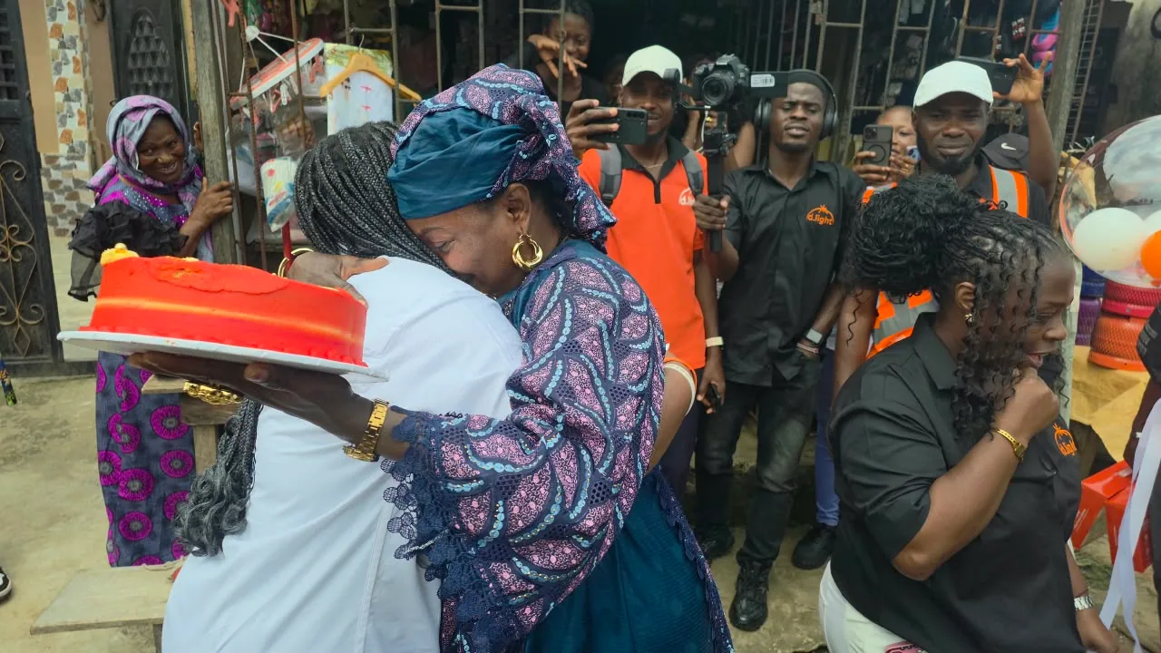 Two people embrace beside a birthday cake.